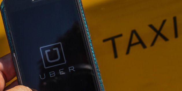 BARCELONA, SPAIN - JULY 01: In this photo illustration, the new smart phone app 'Uber' logo is displayed on a mobile phone next to a taxi on July 1, 2014 in Barcelona, Spain. Taxi drivers in main cities strike over unlicensed car-halling services. Drivers say that is a lack of regulation behind the new app. (Photo Illustration by David Ramos/Getty Images)