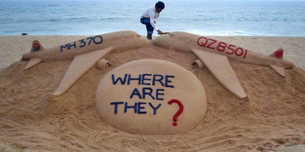 Indian sand artist Sudarsan Pattnaik gives the final touches to his sand sculpture portraying two missing aircraft, Air Asia QZ8501 and Malayasia Airlines MH370 on Golden Sea Beach at Puri, some 65 kms east of Bhubaneswar on December 29, 2014. An AirAsia Airbus plane with 162 people on board went missing en route from Surabaya in Indonesia to Singapore early on December 28, officials and the airline said, in the third major incident to affect a Malaysian carrier this year. AFP PHOTO/STR (Photo credit should read STRDEL/AFP/Getty Images)