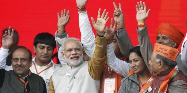 NEW DELHI, INDIA - FEBRUARY 3: Prime Minister Narendra Modi waves alongside Bharatiya Janata Party (BJP) members during a public rally for the upcoming Delhi Assembly Elections, on February 3, 2015 in New Delhi, India. Modi launches an all-out frontal attack on AAP, says those who knew who have accounts in Swiss banks, who kept such names in their pockets, are now saying we don't know who gave us money. He mocks at Aam Aadmi Party, calls it a 'temporary party'. He promises abundant power supply in the national capital. (Photo by Virendra Singh Gosain/Hindustan Times via Getty Images)
