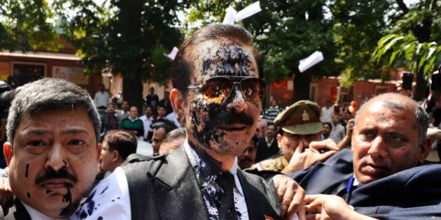Chairman of Sahara India Pariwar Subrata Roy, his face smeared with ink thrown by a lawyer, walks into the Supreme Court in New Delhi, India, Tuesday, March 4, 2014. A lawyer threw ink at the top Indian businessman as he arrived at India's highest court Tuesday to face charges that his company failed to return billions of dollars to investors. Roy's Sahara conglomerate is well known throughout India because it co-owns a Formula One team and sponsored the Indian cricket team until recently. (AP Photo)