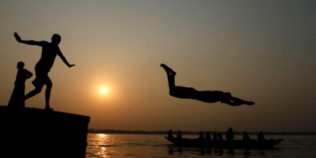 An Indian boy dives into the River Ganges, as tourists ride a boat in Varanasi, India, Thursday, Sept. 27, 2012. Varanasi is among the world's oldest cities, and millions of Hindu pilgrims gather annually here for ritual bathing and prayers in the Ganges river considered holiest by Hindus. (AP Photo/Rajesh Kumar Singh)