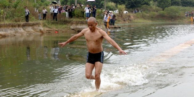 QUANZHOU, CHINA - OCTOBER 26: (CHINA OUT) Shi Liliang, a monk of Shaolin Temple, runs on plywoods which float on water on October 26, 2014 in Quanzhou, Fujian province of China. Shi Liliang, a monk of Shaolin Temple, perfromed water run and broke his record of 100 meters with 118 meters on Sunday. (Photo by ChinaFotoPress/ChinaFotoPress via Getty Images)
