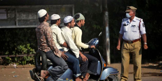 An Indian police officer controls traffic as Muslim men arrive in a scooter to offer prayers on Eid al-Adha in Hyderabad, India, Monday, Nov. 7, 2011. (AP Photo/Mahesh Kumar A.)