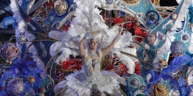 A nominee for Queen of the Carnival of Santa Cruz shows off her outfit on the main stage in Santa Cruz de Tenerife on the Spanish Canary island of Tenerife on February 11, 2014. The dresses are more than five meters high and over 80 kilos in weight. The over one-month-long event began on January 21 and finishes on March 8 with orchestras playing Caribbean and Brazilian rhythms throughout the festivities that range from elections for the Carnival Queen, the Junior Queen and the Senior Queen, children and adult murgas (satirical street bands), comparsas (dance groups) to performances on the streets. AFP PHOTO / DESIREE MARTIN (Photo credit should read DESIREE MARTIN/AFP/Getty Images)