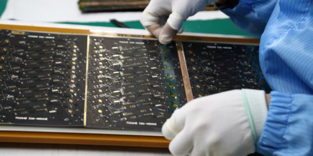 An employee attaches protective film to a Flexible Printed Circuit Board (F-PCB) panel on the production line at the Seil Electronics Co. factory in Incheon, South Korea, on Wednesday, Aug. 28, 2013. South Korea has surpassed Brazil, Russia and India to become the second-biggest emerging stock market for the first time since 2006, as a stable won and record current-account surplus lure investors. Photographer: SeongJoon Cho/Bloomberg via Getty Images