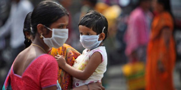 An Indian woman and a child cover themselves with protective masks after the news of the outbreak of swine flu virus as they walk inside the premises of Gandhi Hospital in Hyderabad, India, Wednesday, Jan. 21, 2015. According to local reports, nine people died at the state-run hospital. (AP Photo/Mahesh Kumar A.)