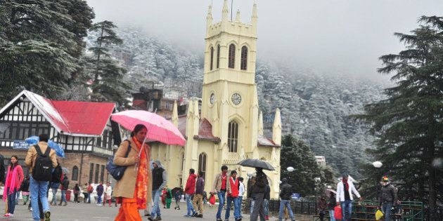 SHIMLA, INDIA - JANUARY 14: People walking at the ridge during snowfall in the backdrop of snow covered Jhaku hill on January 14, 2015 in Shimla, India. Shimla and its surrounding resorts of Kufri, Fagu and Narkanda had another spell of fresh snow while Dhauladhar ranges in Kangra, Churdhar ranges in Sirmaur, Rohtang Pass and higher hills in Chamba district experienced heavy snowfall, throwing normal life out of gear. (Photo by Santosh Rawat/Hindustan Times via Getty Images)