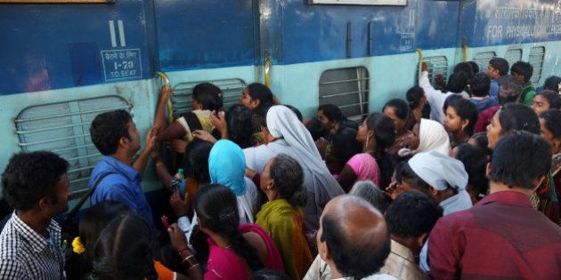 Indian women stand in front of a train door that was closed by a security officer asking them to first form a queue to enter, as people crowd a railway platform in Hyderabad, India, Saturday, Jan. 10, 2015. Railway platforms and trains were overcrowded Saturday as most people travelled to their hometowns to celebrate the Hindu festival of Makar Sankranti that falls on Jan. 14. (AP Photo/Mahesh Kumar A.)