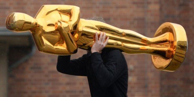 A worker carries an Oscar statue to a press event held by Filmstudios Babelsberg in Potsdam, eastern Germany following the sucess of the 'Grand Budapest Hotel' at the Oscars on February 23, 2015. The film, which was awarded 4 Oscars, Best original soundtrack, Best costume design, Best make-up / hairstyling and Best production design, was co-produced by Filmstudios Babelsberg. AFP PHOTO / DPA / RALF HIRSCHBERGER +++ GERMANY OUT +++ (Photo credit should read RALF HIRSCHBERGER/AFP/Getty Images)