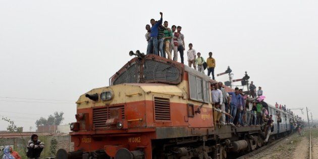 Indian passengers stand and hang onto a train as it departs from a station on the outskirts of New Delhi on February 25, 2015. Indian Railways Minister Suresh Prabhu is scheduled to present the railway budget to parliament on February 26. AFP PHOTO/MONEY SHARMA (Photo credit should read MONEY SHARMA/AFP/Getty Images)