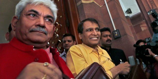 Indian Railway Minister Suresh Prabhu, centre, and junior Railway Minister Manoj Sinha, left, lifts the briefcases containing Railway budget for the year 2015-16 as they arrive at the parliament house to present it in New Delhi, India, Thursday, Feb. 26, 2015. Indian Railways is one of the world's largest and serves more than 23 million passengers a day. (AP Photo/Manish Swarup)