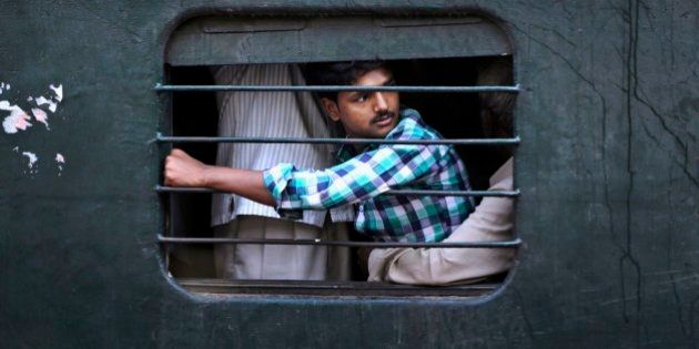 An Indian passenger sits on the lap of another man as he travels in a crowded local train on the outskirts of Kolkata, India, Thursday, Feb. 26, 2015. Indian Railway minister Suresh Prabhu will unveil the Rail Budget 2015 on Thursday for one of the worldâs largest railways systems that serves more than 23 million passengers a day. (AP Photo/Bikas Das)