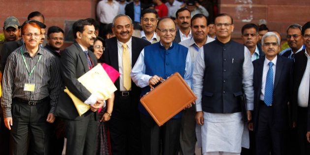 Indian Finance Minister Arun Jaitley, center in blue jacket, display a briefcase containing union budget for the year 2015-16 as he leaves his office for Parliament to present the union budget in New Delhi, India, Saturday, Feb. 28, 2015. (AP Photo/Altaf Qadri)