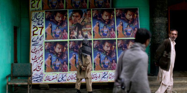 In this Sunday, April 29, 2012 photo, a Pakistani man looks at a board displayed on it advertisements of a local movie, outside Taj Mahal cinema in Abbottabad, Pakistan. One year since U.S. commandos flew into this army town and killed Osama bin Laden, Pakistan has tried to close one of the most notorious chapters in its history. The compound that housed him for six years was razed to the ground, and the wives and children who shared the hideaway were flown to Saudi Arabia just last week. (AP Photo/Muhammed Muheisen)