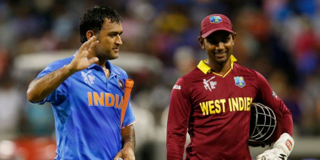 Indian captain M S Dhoni, left, waves to the crowd as he walks from the field with West Indies wicketkeeper Denesh Ramdin following their four wicket win in their Cricket World Cup Pool B match in Perth, Australia, Friday, March 6, 2015. (AP Photo/Theron Kirkman)