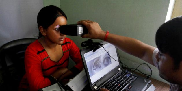 An Indian girl, left, gets her retina scanned as she enrolls for Aadhar, Indiaâs unique identification project in Kolkata, India, Wednesday, May 16, 2012. The giant identification project which aims to give everyone an identity record and number for the first time involves recording retina scans, fingerprints and photographs of all 1.2 billion Indians. (AP Photo/Bikas Das)