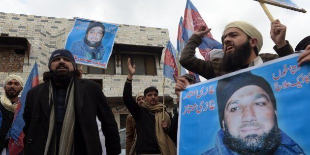 Pakistani Islamist and supporters of former police bodyguard Mumtaz Qadri, hold his portrait as they shout slogans calling for his release during a protest outside the high court building in Islamabad on February 3, 2015. A former Pakistan police bodyguard appealed February 3 against his death sentence for murdering a provincial governor who sought reform of blasphemy laws, as hundreds rallied outside the court to show support. AFP PHOTO / Aamir QURESHI (Photo credit should read AAMIR QURESHI/AFP/Getty Images)