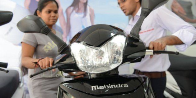 A picture taken on October 8, 2014 shows a woman (L) looking at the recently launched Mahindra Gusto scooter at a Mahindra Two Wheelers Authorised Showroom in Ahmedabad. Mahindra Two Wheelers, a part of USD 16.5-billion Mahindra Group, has entered into a binding bid to acquire 51 percent stake for Rs216 crore, or 28 million, in Peugeot Motorcycles, an affiliate of the 54-billion PSA group. AFP PHOTO / Sam PANTHAKY (Photo credit should read SAM PANTHAKY/AFP/Getty Images)