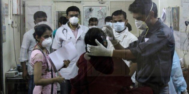 Indian medical staff attending to a patient are seen through the glass of an isolation ward for swine flu at the Civil Hospital in Ahmadabad, India, Wednesday, Feb. 25, 2015.The west Indian city has banned large public gatherings in an attempt to halt the spread of swine flu, which has claimed more than 900 lives nationwide in 11 weeks. (AP Photo/Ajit Solanki)
