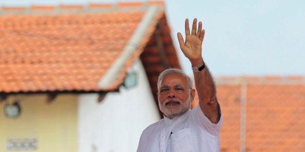 Indian Prime Minister Narendra Modi waves to the gathering during the handing over of homes under a housing scheme funded by the Indian government for war victims in Llavalai, northwest of Jaffna, Sri Lanka, Saturday, March 14, 2015. During his visit to north, Modi commissioned a section of railway track built with Indian aid in Talaimannar and ceremonially began the construction work of a cultural center to be built in the town of Jaffna with Indian assistance. Jaffna is the cultural heartland of the Tamils and was the stage of many battles during Sri Lanka's quarter century civil war. (AP Photo/Eranga Jayawardena)
