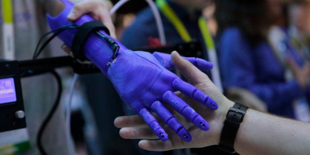 An attendee shakes hands with a 3D-printed robotic prosthetic arm created based on an image scanned with Intel's RealSense 3D camera, at the International CES Wednesday, Jan. 7, 2015, in Las Vegas. (AP Photo/Jae C. Hong)