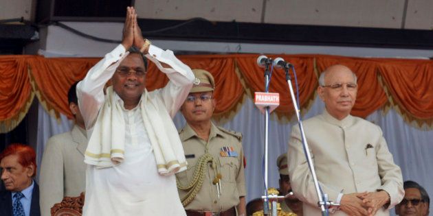India's ruling Congress party leader and new Chief Minister of Karnataka state K. Siddaramaiah, left, greets his supporters after administering the oath of office in the presence of Governor H.R. Bhardwaj, right, at the Kanteerva Stadium in Bangalore, India, Monday, May 13, 2013. Siddaramaiah, 64, administered the oath of office Monday in front of thousands of supporters marking the return of the administration back to the hands of Congress, in the state, after more than 7 years, according to local reports. (AP Photo/Kashif Masood)