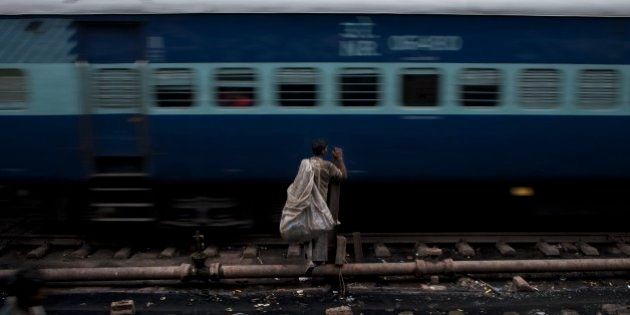 An Indian ragpicker waits for a train to pass by as he tries to cross railway tracks in New Delhi, India, Wednesday, Feb. 25, 2015. India on Thursday is expected to table the 2015 budget for the national railways system, which is one of the world's largest and serves more than 23 million passengers a day. (AP Photo/Bernat Armangue)