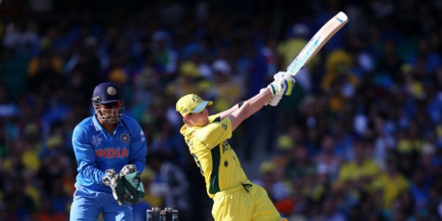 Australia's Steve Smith hits the ball for six runs as India's MS Dhoni watches during their Cricket World Cup semifinal in Sydney, Australia, Thursday, March 26, 2015. (AP Photo/Rick Rycroft)
