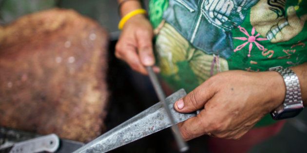 A butcher sharpens a knife before cutting buffalo meat, unseen, at a beef store in New Delhi, India, on Wednesday, March 11, 2015. The government of the state of Maharashtra last week banned possession of beef and its byproducts and the slaughtering of cows, bulls and bullocks. The prohibition marks a victory for hard-line Hindu groups that have sought to protect an animal their religion considers holy. Photographer: Prashanth Vishwanathan/Bloomberg via Getty Images