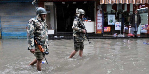 SRINAGAR, INDIA - MARCH 29: Paramilitary soldiers walks along flooded roads following heavy rain on March 29, 2015 in Srinagar, India. Intermittent rainfall across Kashmir raised water level of streams and rivers, triggering panic among resident of floods. The valley has been witnessing heavy rainfall since Saturday, leading to a sudden surge in water level in rivers, streams and rivulets. The Met Department has predicted more rain over the next six days with heavy rain expected today and on April 3. (Photo by Waseem Andrabi/Hindustan Times via Getty Images)