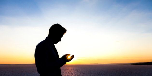 Young man praying at sunset