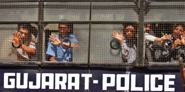 Convicted Indians wave to their families from inside a police vehicle as they are taken away after the pronouncement of sentence at a district court in Anand, about 75 kilometer (47 miles) from Ahmedabad, India, Thursday, April 12, 2012. A court in India has sentenced 18 Hindus to life imprisonment for killing 23 Muslims during religious riots in western India a decade ago. More than 1,000 people, mostly Muslims, died in communal violence that erupted in Gujarat after 60 Hindus were killed in a train fire. The Gujarat riots were one of the worst outbreaks of religious violence in India in the past few decades. (AP Photo/Ajit Solanki)