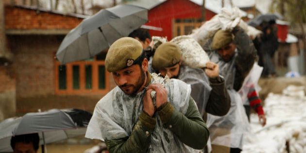 Jammu and Kashmir policemen carry sand bags to repair a breach in an embankment in a flooded area of Srinagar, Indian-controlled Kashmir, Wednesday, April 1, 2015. Although flood waters were receding, residents in the main city of Srinagar were bracing for more trouble as the meteorological office has predicted more rain over the next few days. (AP Photo/Mukhtar Khan)