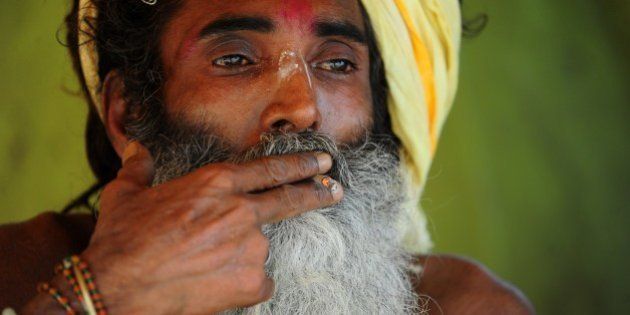 An Indian sadhu, or holy man, smokes a hand-rolled beedi cigarette as he rests near Sangam, the confluence of the rivers Ganges, Yamuna and the mythical Saraswati, on World No Tobacco Day in Allahabad on 31May,2014. The World Health Organisation (WHO) and partners mark World No Tobacco Day on May 31, highlighting the health risks associated with tobacco use. AFP PHOTO/SANJAY KANOJIA (Photo credit should read Sanjay Kanojia/AFP/Getty Images)