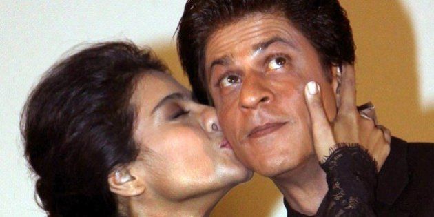 Indian Bollywood film actors Shah Rukh Khan (R) and Kajol Devgan pose during the celebration of the successful completion of 1000 weeks of screenings, since its release in 1995, of their romantic Hindi film 'Dilwale Dulhania Le Jayenge' (DDLJ) written and directed by then-debutante director Aditya Chopra and produced by his father, the late Yash Chopra during a special screening at the Maratha Mandir theatre in Mumbai on December 12, 2014. DDLJ is the longest running Bollywood film ever, beating the previous record holder, Sholay. AFP PHOTO (Photo credit should read STR/AFP/Getty Images)