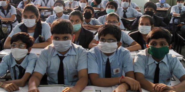 Indian students wear masks for protection against swine flu, as they attend their class at a school in Ahmadabad, Gujarat state, India, Monday, March 2, 2015. Thousands in Gujarat were tested positive for H1N1, the virus which causes swine flu. (AP Photo/Ajit Solanki)