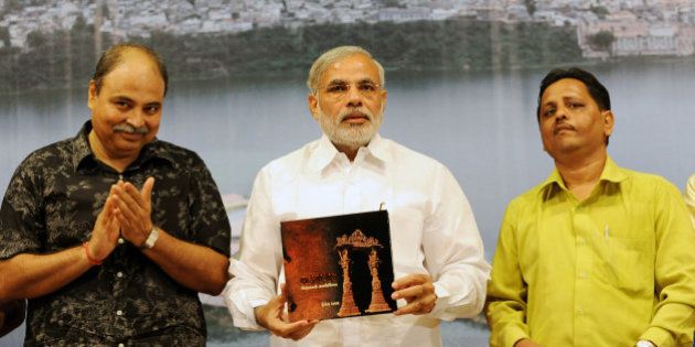Gujarat state Chief Minister Narendra Modi (C) holds up a copy of the book 'Vadnagar- Virasat no Tasviri Vaibhav', authored by Principal Photographer of India Today Shailesh Raval (R) and India Today's Special Correspondent Uday Mahurkar (L), during a launch in Ahmedabad on October 4, 2009. Vadnagar, with its rich heritage and historical importance, is regarded as a cultural capital of the region. AFP PHOTO/ Sam PANTHAKY (Photo credit should read SAM PANTHAKY/AFP/Getty Images)