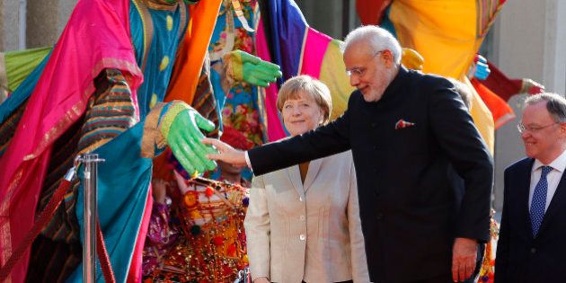 German Chancellor Angela Merkel, center, welcomes India's Prime Minister Narendra Modi, second right, as a traditional Indian music group performs at the opening of the industrial fair in Hanover, Germany, Sunday, April 12, 2015. India is this years' partner country and participates in one of the worlds biggest industrial fairs that lasts till April 17,2015. (AP Photo/Frank Augstein)