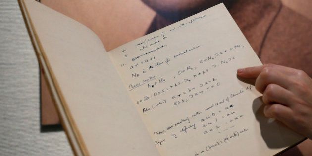 FILE - In this March 19, 2015, file photo, a page from the notebook of British mathematician and pioneer in computer science Alan Turing, the World War II code-breaking genius, is displayed in front of his portrait during an auction preview in Hong Kong. The 56-page manuscript, containing Turing's complex mathematical and computer science notations, is being sold by Bonhams in New York on Monday, April 13. (AP Photo/Kin Cheung, File)