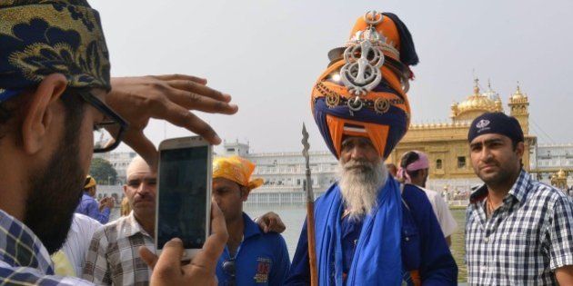 An Indian Sikh devotee (L) takes photographs of a Nihang (Sikh religious warrior) at the Sikh shrine Golden Temple in Amritsar on April 14, 2015. Baisakhi is a festival celebrated in the Punjab region, coinciding with other festivals celebrated on the first day of Vaisakh such as the Tamil and Bengali New Year. AFP PHOTO/NARINDER NANU (Photo credit should read NARINDER NANU/AFP/Getty Images)