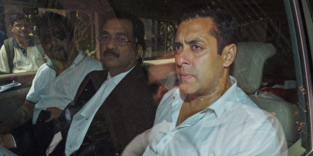 Bollywood actor Salman Khan, right, sits in a car outside a court in Mumbai, India, Friday, March 27, 2015. Khan refuted charges that he was driving the car which had rammed into a bakery shop in Mumbai on Sept. 28, 2002, killing one person and injuring four others who were sleeping on the pavement. (AP Photo/Press Trust of India)