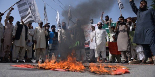 Pakistani activists from the banned organisation Jamaat-ud-Dawa (JuD) shout slogans beside a burning Indian flag during a protest in Islamabad on April 17, 2015, against the arrest of an Indian Kashmir prominent separatist leader Masarat Alam Bhat by Indian police in Srinagar. Police arrested a prominent separatist leader in Indian-administered Kashmir on April 17 after he headlined at a rally where supporters waved Pakistani flags and chanted pro-Pakistan slogans. Masarat Alam Bhat, who was released in March after several years behind bars, was arrested at his home in the main city of Srinagar, a day after police registered a case against him for 'anti-national' activities. AFP PHOTO/ Aamir QURESHI (Photo credit should read AAMIR QURESHI/AFP/Getty Images)
