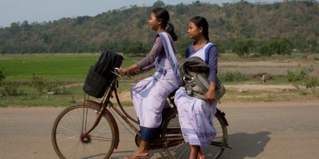 Indian girls go to a school on a bicycle at Roja Mayong village about 40 kilometers (25 miles) east of Gauhati, India, Thursday, April 9, 2015. According to the UNESCO Education for All Global Monitoring Report 2015, only half of all countries have achieved the most watched goal of universal primary enrollment. The report launched Thursday says, India has reduced its out of school children by over 90% Since 2000. (AP Photo/ Anupam Nath)