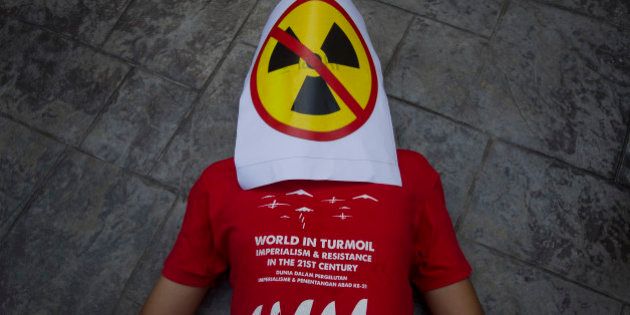 A protestor lies on the ground with an anti-nuclear placard covering his face during a protest in Bangi outside Kuala Lumpur, Malaysia on Tuesday, April 21, 2015. In conjunction with the World Earth Day on April 22, about a dozen protestors from the Malaysia Socialist Party gathered outside the Malaysia Nuclear Agency to protest the development plans of nuclear reactor in Malaysia. (AP Photo/Joshua Paul)