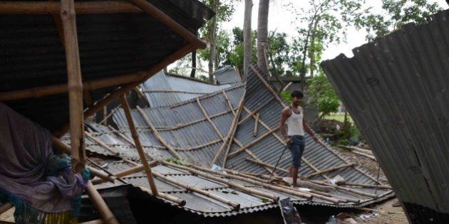 An Indian resident walks on the roof of his shattered home in the village of Gazole, Malda District some 250kms east of Patna on April 22, 2015, after an overnight storm hit many states of eastern India. A powerful storm swept through India's eastern states including Bihar and West Bengal overnight leaving at least 33 people dead and destroying crops and properties, officials and a report said. The storm lashed several districts across the impoverished state of Bihar, uprooting trees and toppling power lines, the officials said. AFP PHOTO/STR (Photo credit should read STRDEL/AFP/Getty Images)