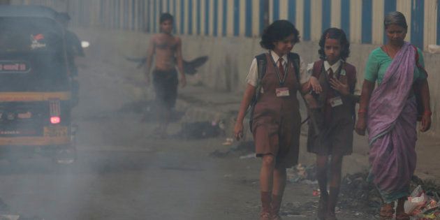 Schoolgirls walk past a burning garbage dump in Mumbai, India, Thursday, April 9, 2015. Air pollution kills millions of people every year, including more than 627,000 in India, according to the World Health Organization. The WHO puts 13 Indian cities in the world's 20 most polluted. (AP Photo/Rafiq Maqbool)