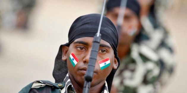 An Indian Central Reserve Police Force (CRPF) personnel with national flag painted on his face participates in arms drill during the passing out parade ceremony of 945 recruits in Bangalore, India, Tuesday, July 9, 2013. CRPF is one of the largest paramilitary force in the world with a strength of over 250,000 personnel, meant to maintain law and order and contain insurgency across India and are also deployed for United Nations missions. (AP Photo/Aijaz Rahi)