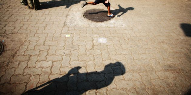 MUMBAI (BOMBAY), INDIA - DECEMBER 03: (ISRAEL OUT) A policeman's silhouette is cast on the ground as a child plays outside the Jewish appartment block, Nariman House, on December, 03, 2008 in Mumbai, India. Two bombs were discovered and defused earlier today by Mumbai police at a train station, the Chhatrapati Shivaji Terminus, which was one of the locations attacked by the terrorists. The attacks left almost 200 hundred dead and injured over 300 people. (Photo by Uriel Sinai/Getty Images)