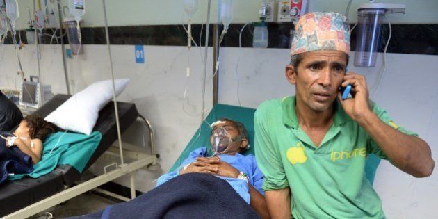A Nepalese resident talks on the phone as his relative Megh Nath (2R), is treated for injuries sustained in an earthquake at a city hospital in Kathmandu on April 26, 2015. International aid groups and governments intensified efforts to get rescuers and supplies into earthquake-hit Nepal on April 26, 2015, but severed communications and landslides in the Himalayan nation posed formidable challenges to the relief effort. As the death toll surpassed 2,000, the US together with several European and Asian nations sent emergency crews to reinforce those scrambling to find survivors in the devastated capital Kathmandu and in rural areas cut off by blocked roads and patchy phone networks. AFP PHOTO / PRAKASH SINGH (Photo credit should read PRAKASH SINGH/AFP/Getty Images)