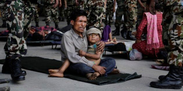 A man sits with a child on his lap as victims of Saturdayâs earthquake, wait for ambulances after being evacuated at the airport in Kathmandu, Nepal, Monday, April 27, 2015. The death toll from Nepal's earthquake is expected to rise depended largely on the condition of vulnerable mountain villages that rescue workers were still struggling to reach two days after the disaster. (AP Photo/Altaf Qadri)